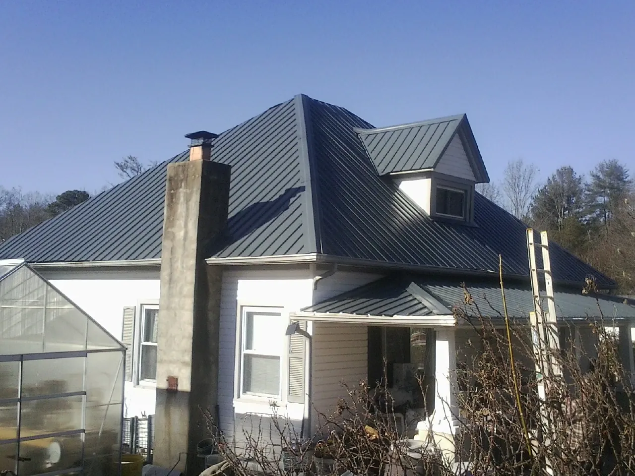 Dark blue standing seam metal roof on a white farmhouse with dormer — Slate & Tile Roof Repair by Roofing Brothers in Vernon Hills