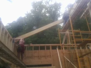 Carpenter raising a rafter beam on a new second story frame in Vernon Hills