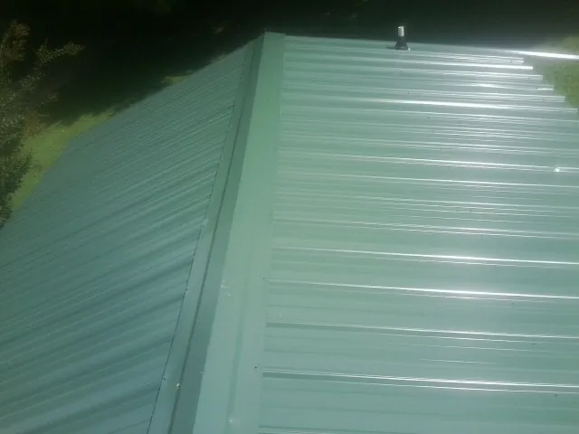 New green metal panels meeting at the ridge of a roof — Flat Roof Repair work by our crew in Vernon Hills