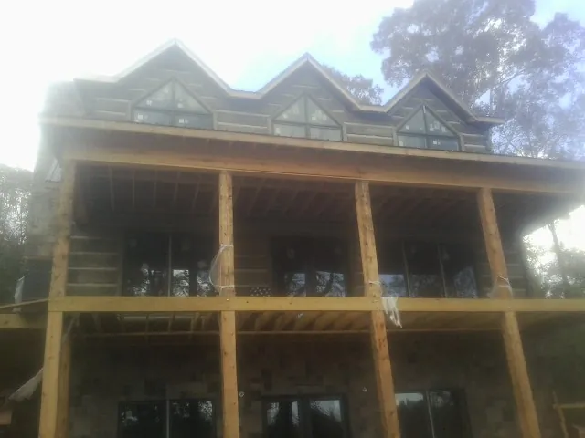 Dormers and porch framing on a large log home under construction — Roof Coating work by our crew in Vernon Hills