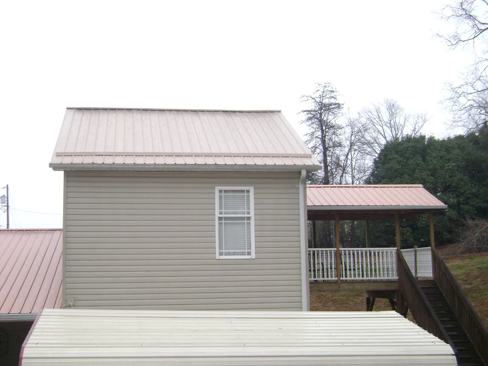 Tan metal roofs on a two story addition and attached porch, from a Roof Replacement job in Vernon Hills