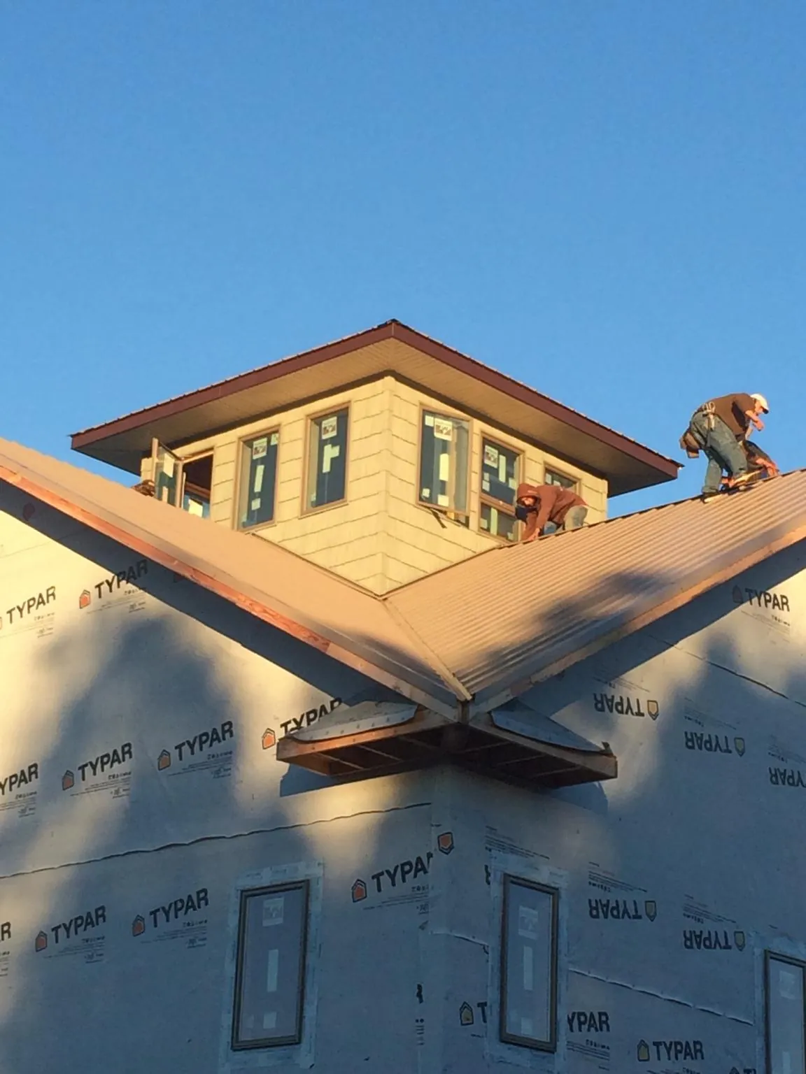 Roofers working around a rooftop cupola on a new metal roof at sunset — Roof Waterproofing in Vernon Hills by Roofing Brothers